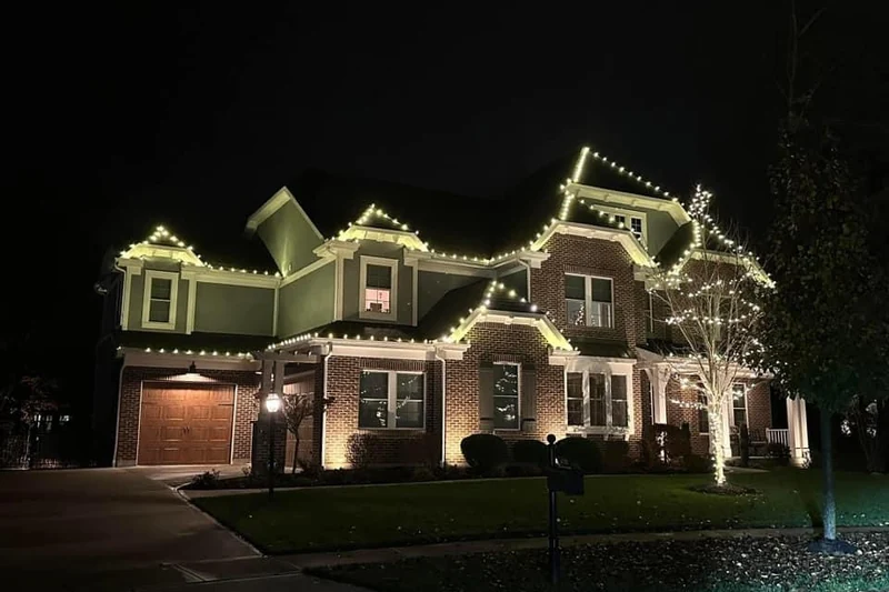 Two storey home with warm white Christmas lights following every roofline and dormer, shot at night from the street