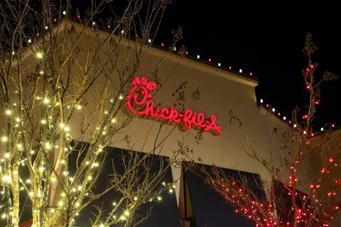 Storefront with warm white wrapped trees and red accent lighting framing the building signage