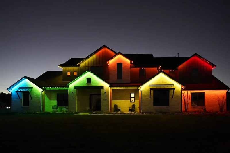 Two storey home outlined in saturated multicolor lighting across every roofline, gable and window
